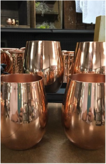 Assortment of copper cups with reflection on them.